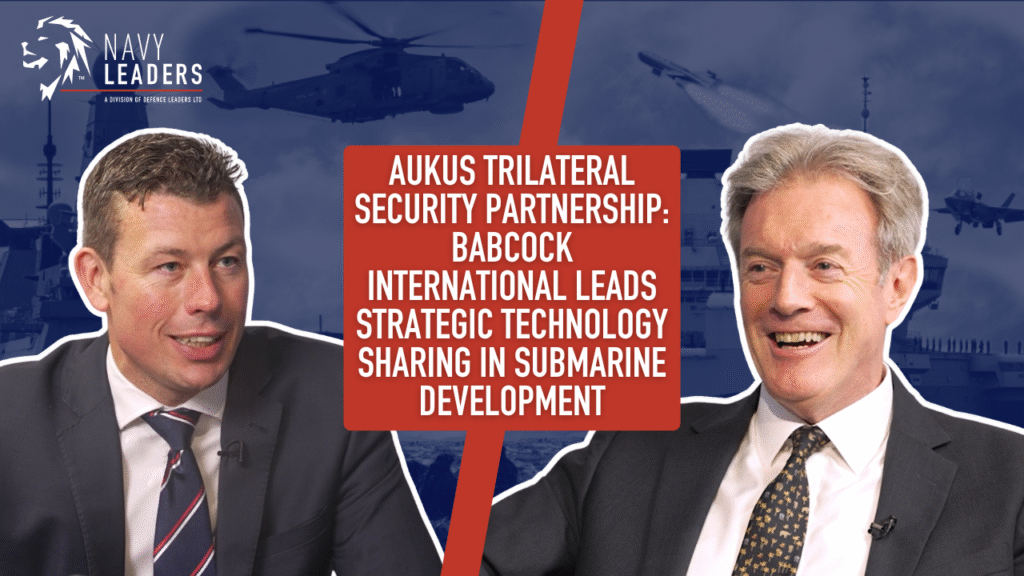 Two men are smiling against a navy-themed background with ships and helicopters. A red box reads: "AUKUS Trilateral Security Partnership..." (text cropped).