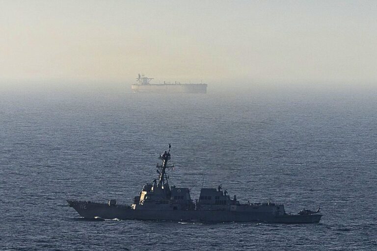 Arleigh Burke-class Aegis guided-missile destroyer USS Michael Murphy sails past a cargo vessel as she helps enforce the U.S. naval blockade.